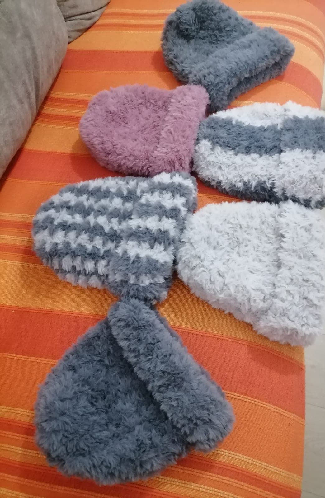 Šest pufnastih kapa u više boja na prugastom prekrivaču